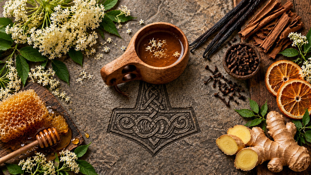 A wooden kuksa cup of mead above a carved Mjölnir hammer, surrounded by honeycomb, elderflower, spices, dried orange and ginger